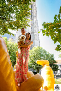 Koppel met hond poseert op het grote gele Opsinjoor-beeld met de Sint-Romboutstoren op de achtergrond tijdens een Cityshoot in Mechelen door fotograaf Stef Boey